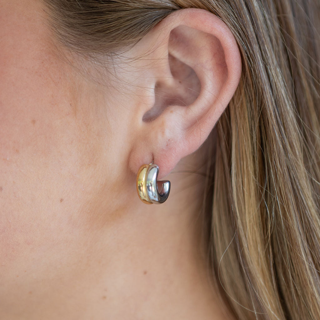 Close-up of an ear wearing a gold and silver hoop earring.