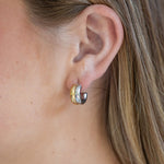 Close-up of an ear wearing a gold and silver hoop earring.