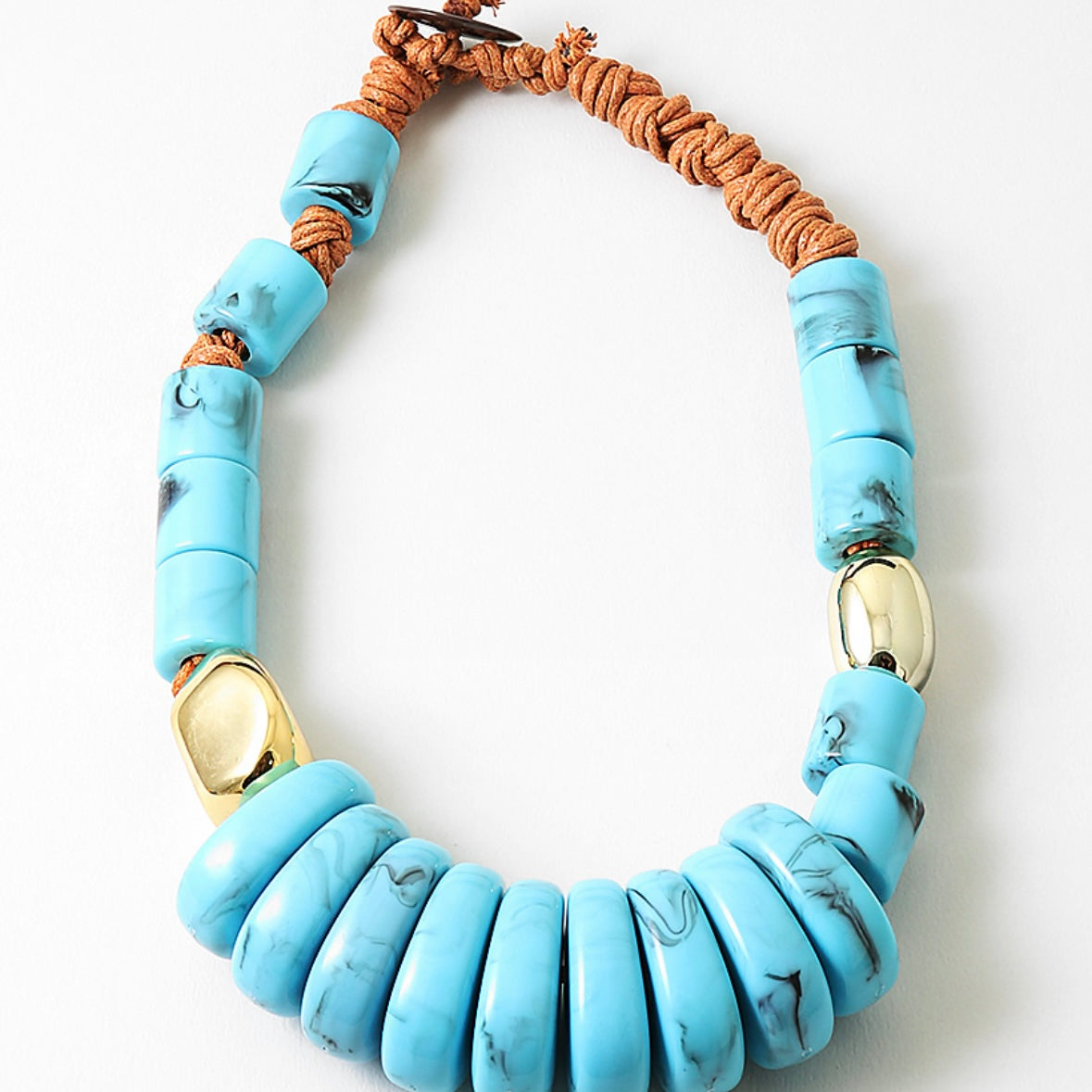 Chunky statement necklace with blue beads and a brown cord on a white background