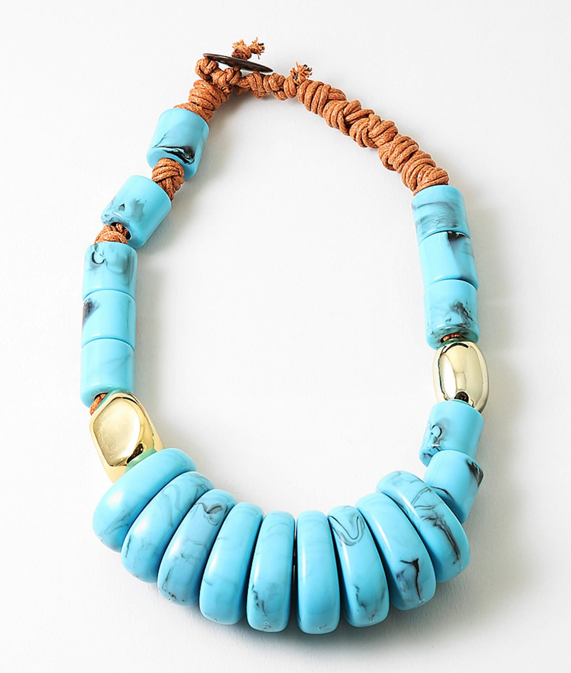 Chunky statement necklace with blue beads and a brown cord on a white background