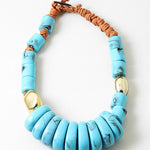 Chunky statement necklace with blue beads and a brown cord on a white background