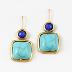 Pair of earrings with gold frames, blue gemstones, and turquoise stones on a white background
