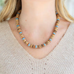 Necklace with brown and blue beads worn by a person in a beige sweater.