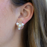 Picture of woman wearing large studs made of fresh water pearls, light pink stones and tiny gold beads.
