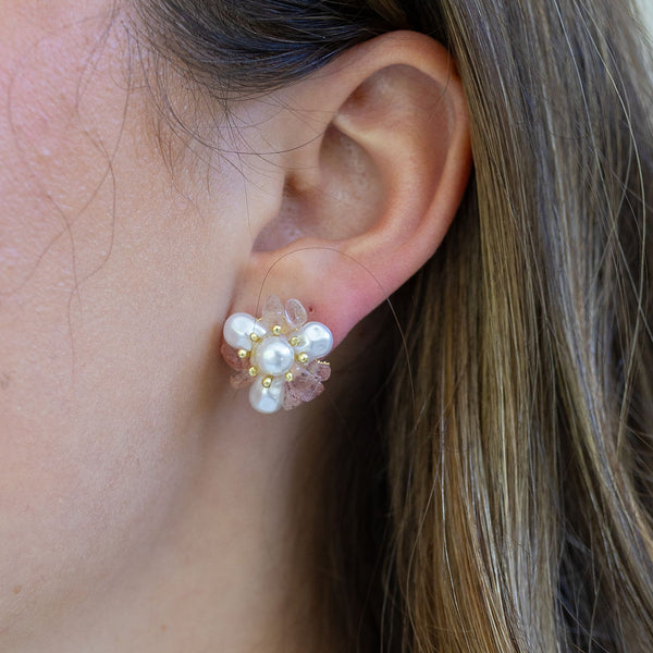 Picture of woman wearing large studs made of fresh water pearls, light pink stones and tiny gold beads.