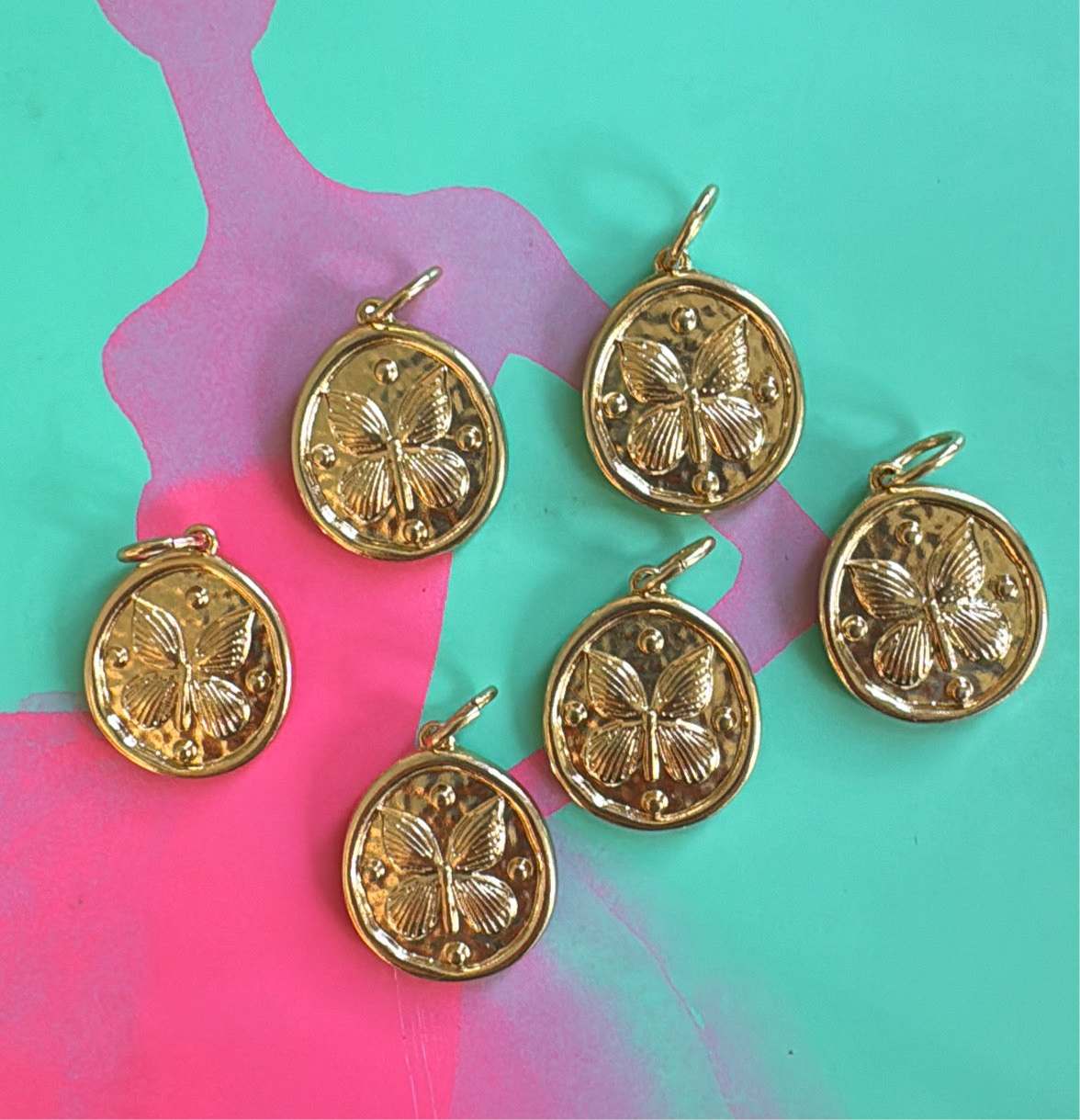 Gold butterfly disc pendants on a colorful abstract background