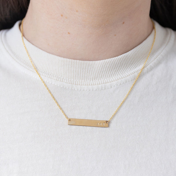 Picture of fine gold chain with a gold bar pendant that reads, "Joy".