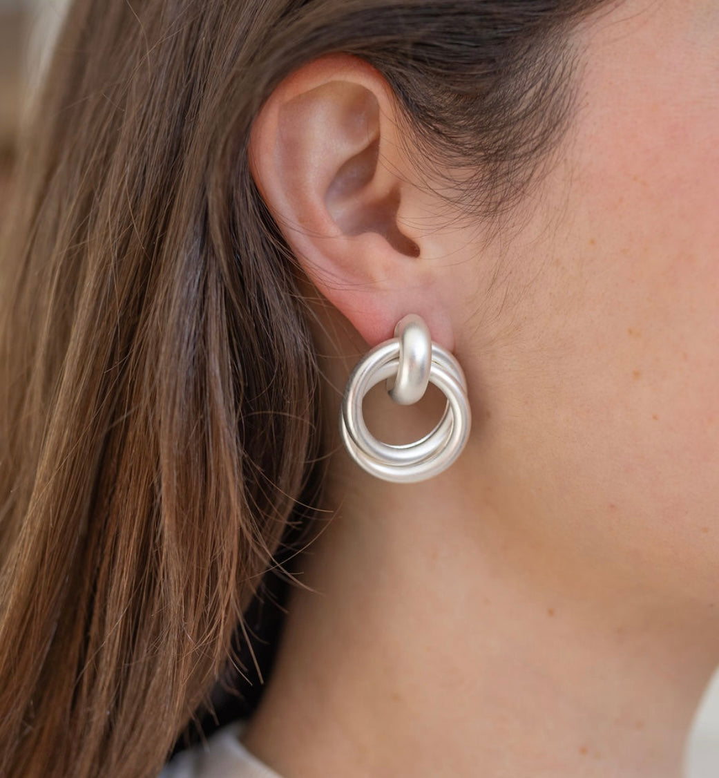 Picture of model wearing white silver looped earrings.