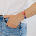 Woman wearing bright multi-colored beaded stretchy bracelet.