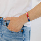 Woman wearing bright multi-colored beaded stretchy bracelet.