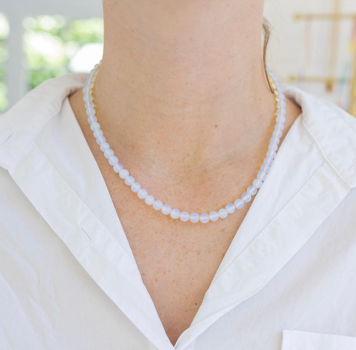 Model wearing an opaque white bead necklace.