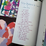 Open notebook with handwritten text on a colorful, patterned surface