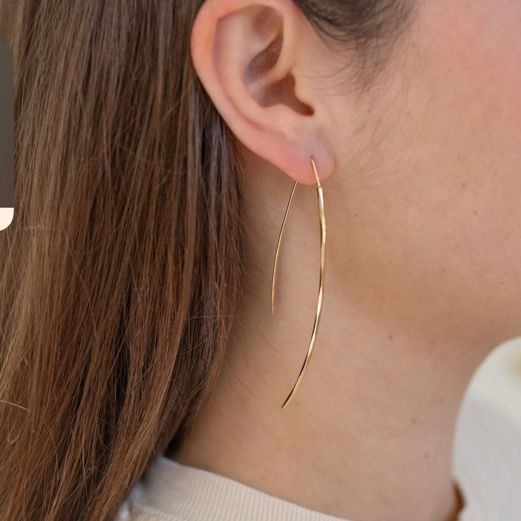 Picture of gold strand earrings threaded through model's ear.