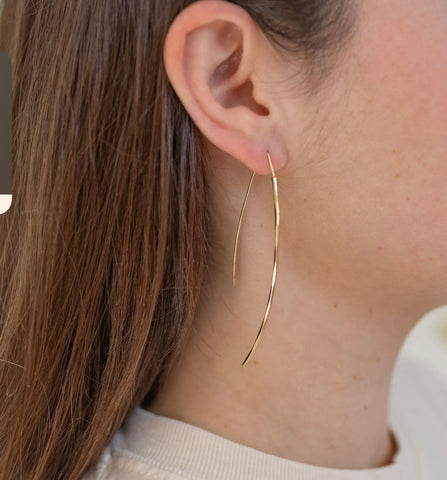 Picture of gold strand earrings threaded through model's ear.
