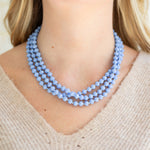 Blue beaded necklace worn by a person with a beige sweater