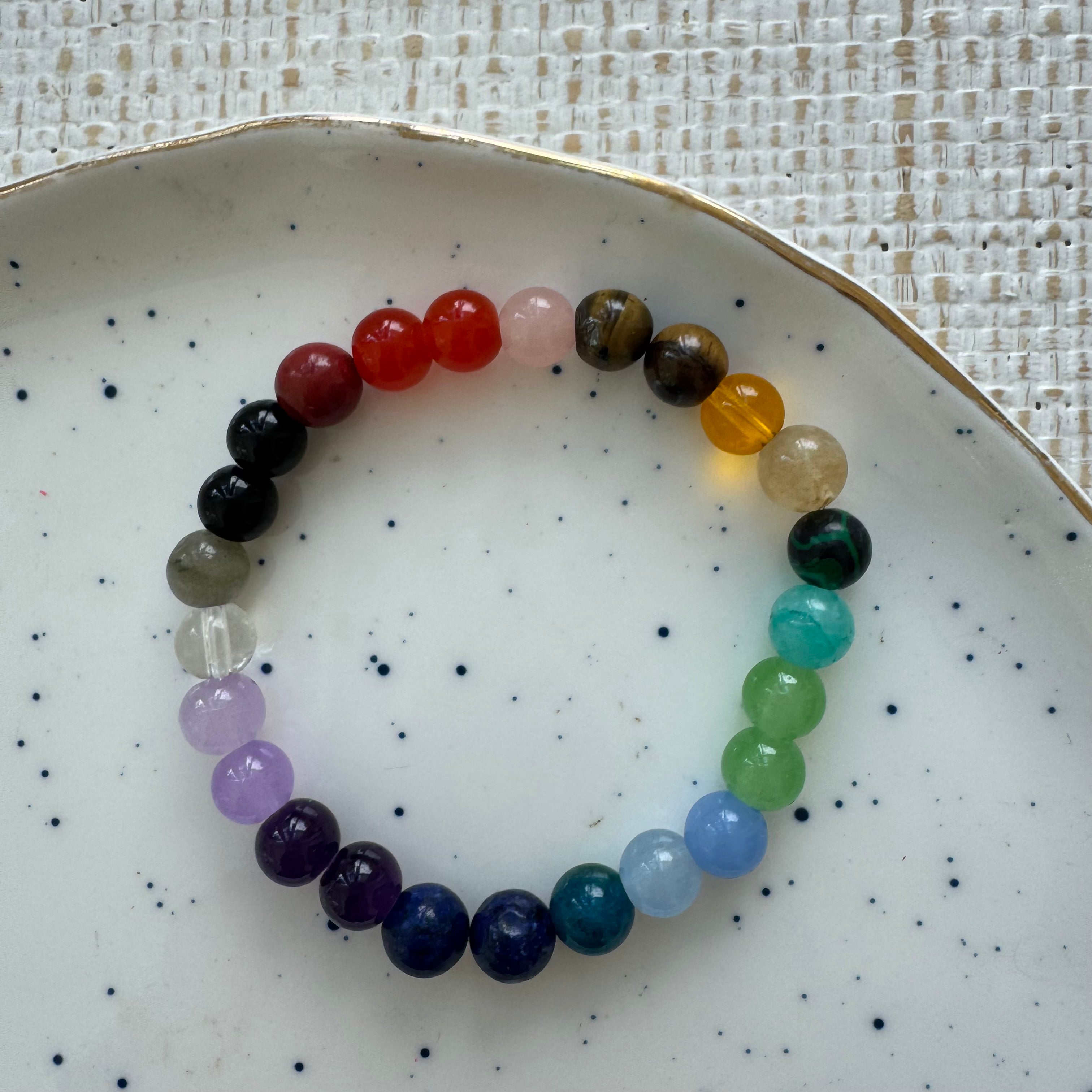 Multicolored beaded bracelet on a white plate with a textured background