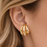 Close-up of a three hoop gold hoop earring worn by a person with blonde hair.