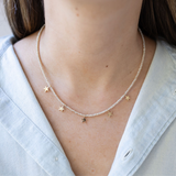 Picture of a dainty white seed bead necklace with tiny gold star beads dangling from it.