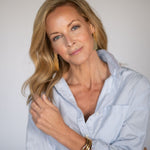 Woman wearing a light blue button up shirt against a plain background