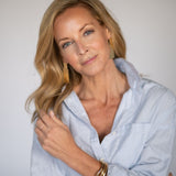 Woman wearing a light blue button up shirt against a plain background