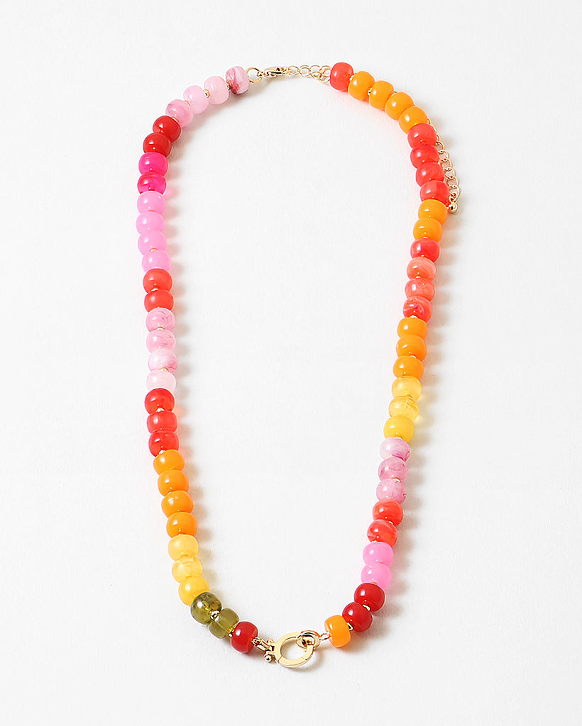 Large bead necklace made of orange, pinks and yellows with a large gold clasp at its center.