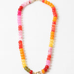 Large bead necklace made of orange, pinks and yellows with a large gold clasp at its center.