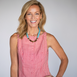 Woman wearing a red checkered dress with a blue necklace against a gray background