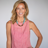 Woman wearing a red checkered dress with a blue necklace against a gray background