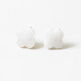 White stud earrings in the shape of rounded crosses.