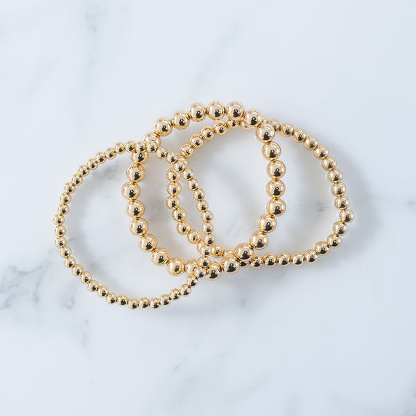 Picture of set of three gold beaded bracelets in varying bead sizes.