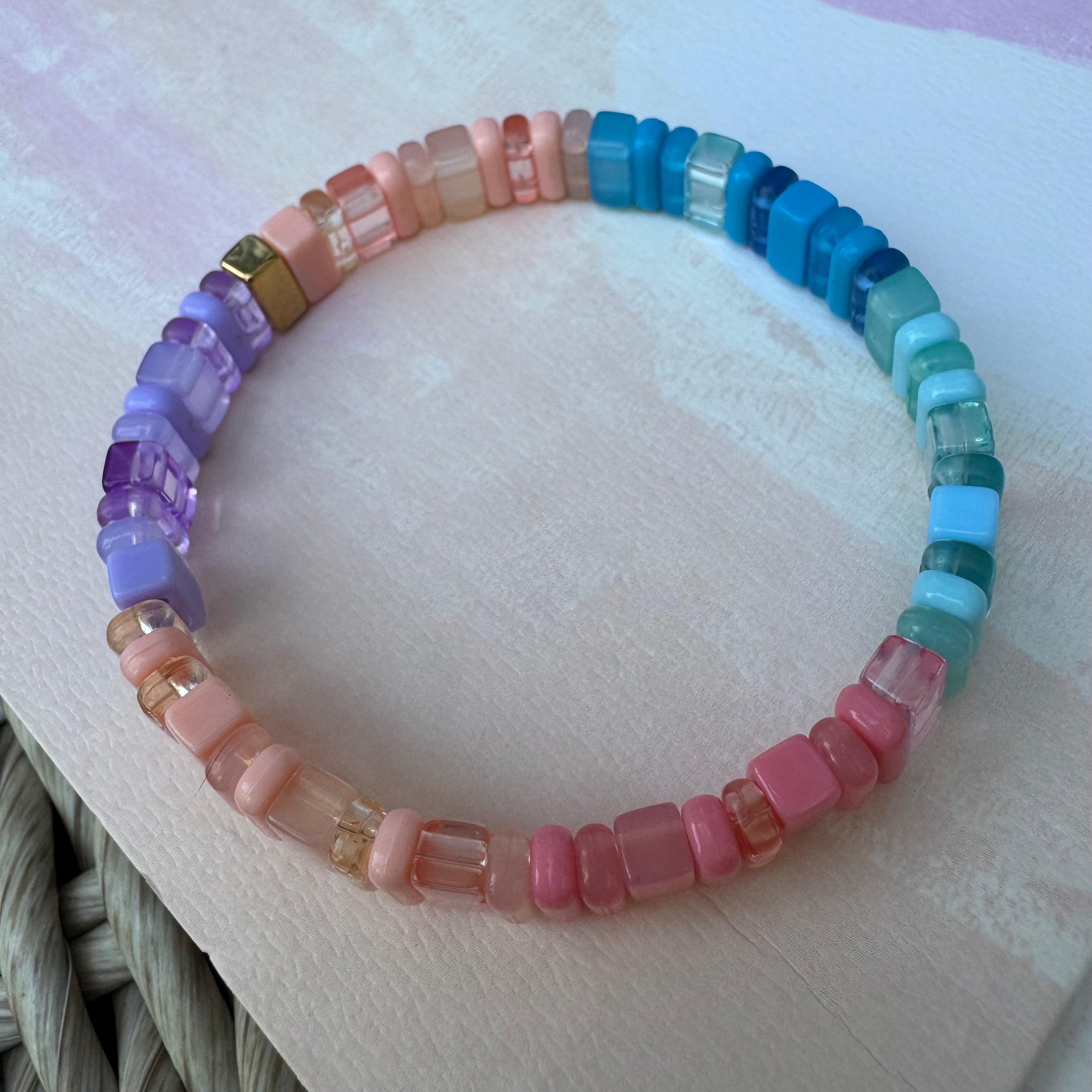 Bead bracelet with varying clear and solid colored beads in shades of purple, coral blues and pinks.