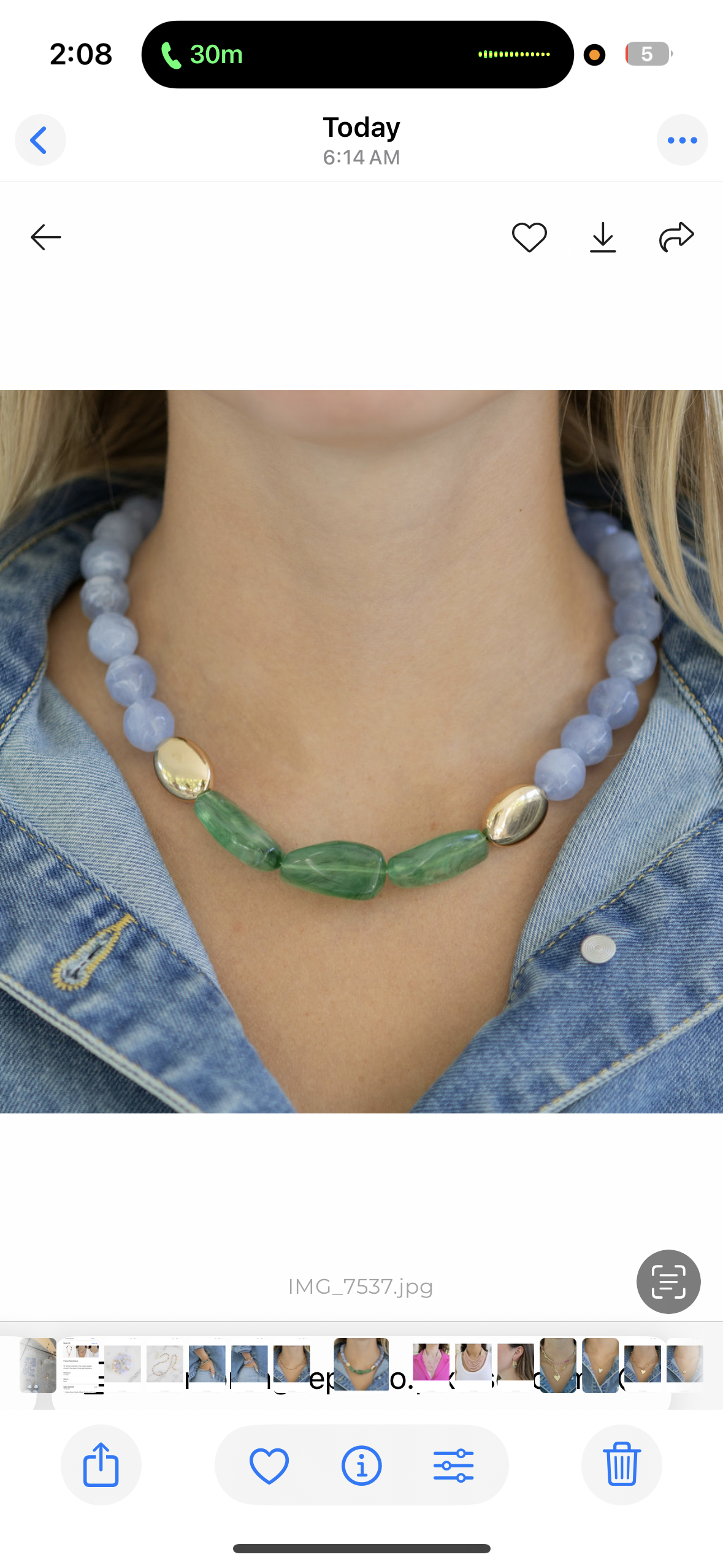 Necklace with green and gold accents worn by a person, displayed on a smartphone screen.