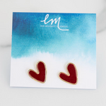 Picture of tiny red heart stud earrings with gold trim on a blue and white watercolor earring holder