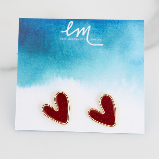 Picture of tiny red heart stud earrings with gold trim on a blue and white watercolor earring holder