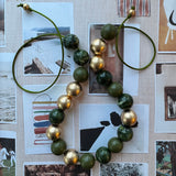 Necklace with green and gold beads on a collage background