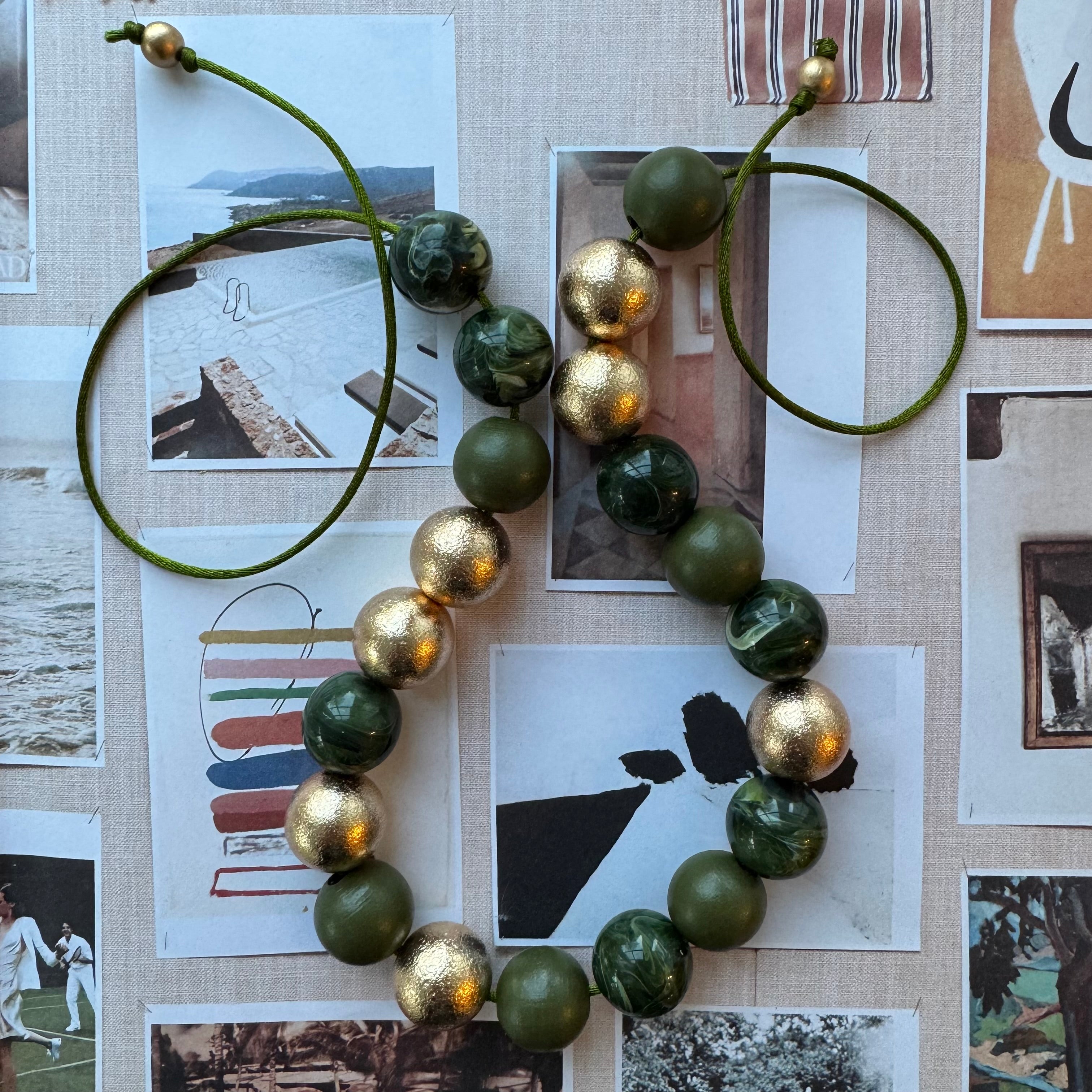Necklace with green and gold beads on a collage background