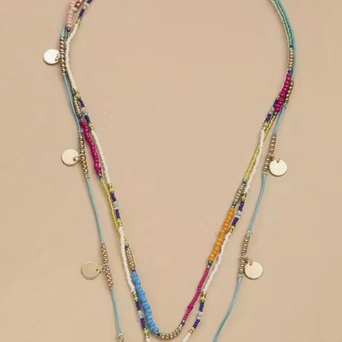 Multistrand beaded necklace with colorful beads and gold accents on a beige background
