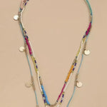 Multistrand beaded necklace with colorful beads and gold accents on a beige background