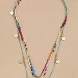 Multistrand beaded necklace with colorful beads and gold accents on a beige background