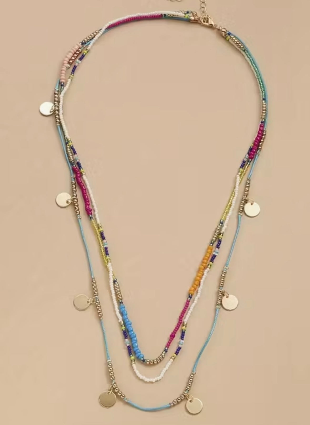 Multistrand beaded necklace with colorful beads and gold accents on a beige background
