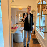 Person taking a mirror selfie in a home setting with a kitchen visible.