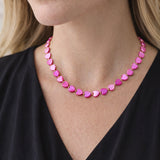 Close-up of a woman wearing a pink heart-shaped beaded necklace against a neutral background