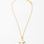 Delicate gold chain necklace with a white cross pendant.