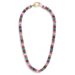 Multicolored beaded necklace in mauve, red, blues and greens on a white background