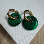 Gold hoop earrings threaded through a large resin green striped bead.