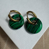 Gold hoop earrings threaded through a large resin green striped bead.