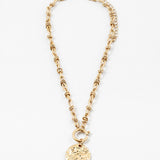 Gold toggle chain necklace with a large hammered disc pendant.