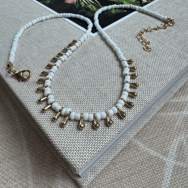 Picture of a white bead bracelet with gold tear drop beads alternating through it's center.