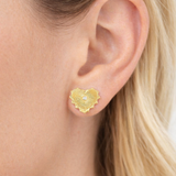 Gold textured heart earring worn by a person with blonde hair.