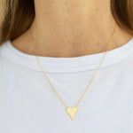 Delicate gold heart necklace worn by a person on a white background